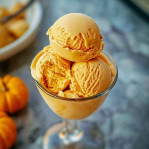 Creamy no-churn pumpkin ice cream in a bowl, topped with cinnamon.